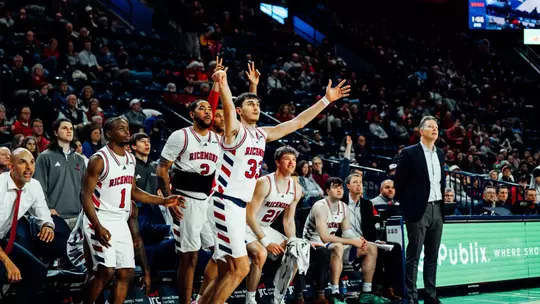 Apostolos Roumoglou shoots a three in front of the Spiders bench