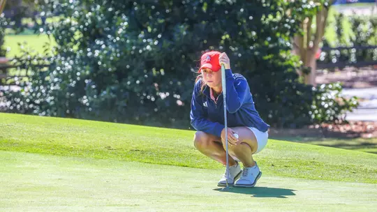 Katie Magner squats to line up a putt