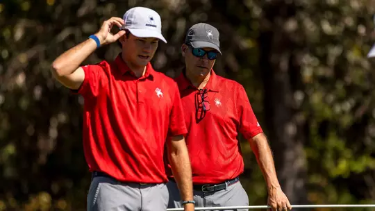 Adam Decker holds a flagstick on the green