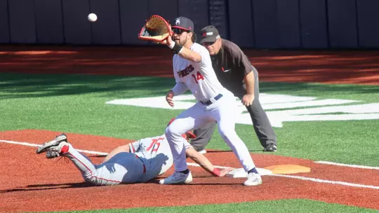 Ryan Recio catches the ball at first on a pick off attempt as the runner dives back into the base