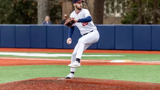 Justin Gay wearing Spider Baseball home all white uniform strides towards home plate and pushes off the mound