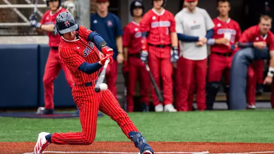 Grant Kennedy wearing the Spiders all red with white pin stripes uniform swings his bat and makes contact with the ball