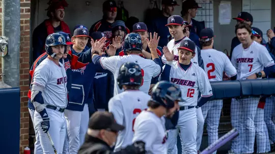 The baseball team high-fives to celebrate scoring a run