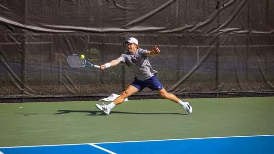 Burdell hitting a tennis ball after a serve