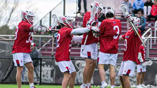 Men's lacrosse players celebrate a goal against UMass on March 21