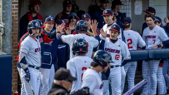 Spider Baseball high fives a teammate as they head into the dugout after scoring