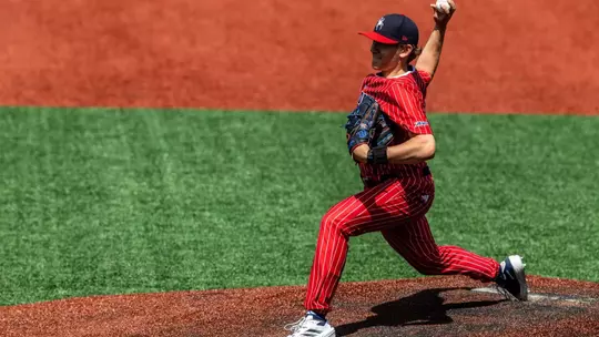 Jackson Hinchliffe holds the ball behind his head, ready to throw the ball towards home plate.