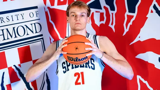 Andrew Ball holds a basketball in front of his chin and stairs at the camera