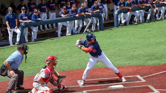 Dylan Winebrenner stands at the plate while the Spiders dugout watches his at bat