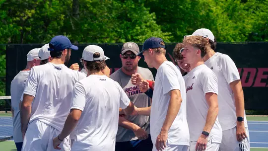 Men's Tennis in a huddle with coach Barrick