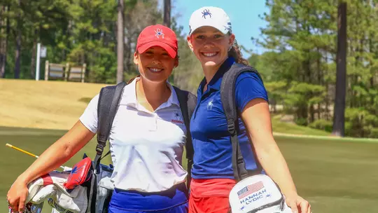 Olivia Wilkie and Hannah Lydic smile at the camera on the green