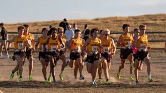 Men's cross country team running at the start line at the Wyoming Invite