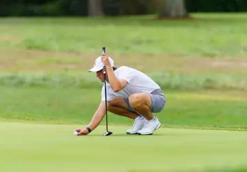 Warren Thomis lining up the golf ball for a putt.