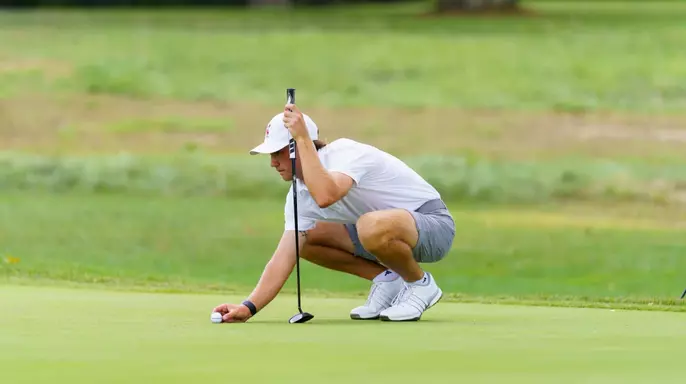 Warren Thomis lining up the golf ball for a putt.