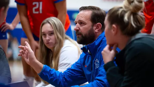 Volleyball Head Coach Shawn Garus talks to the team in a huddle during a timeout.