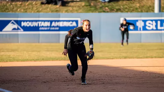 Hollie Farmer charging toward home plate from her third base position.