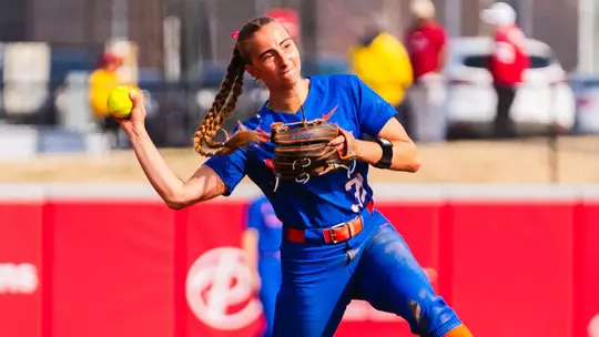 Hollie Farmer in the act of throwing a ball to first base from her third base position.