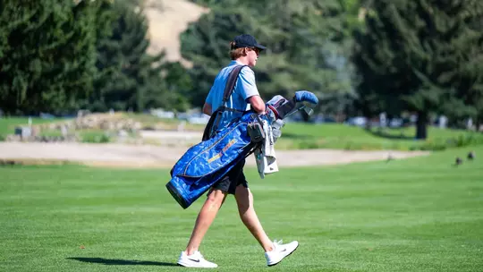 Reese Knox walking while carrying his golf bag