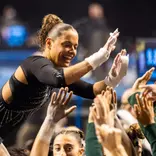 Sage Kellerman celebrates with the team after finishing a bar routine
