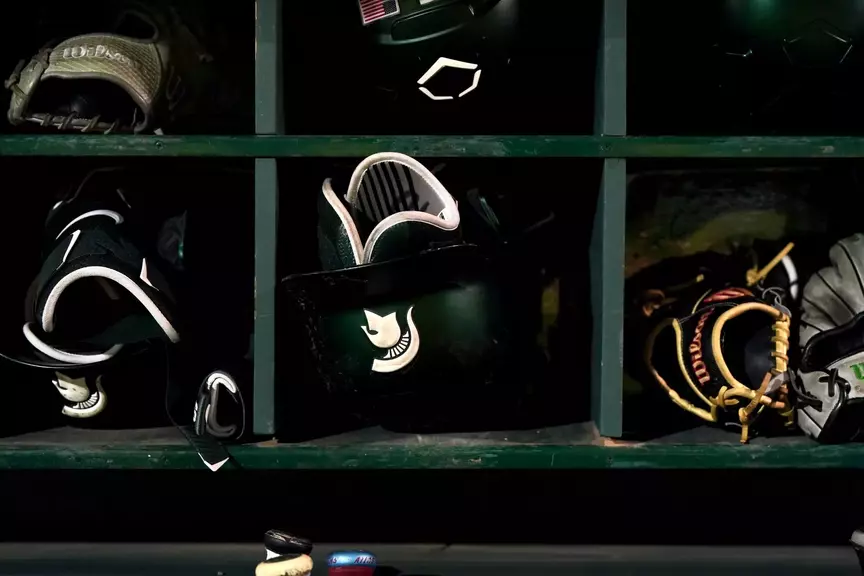 MSU baseball Spartan head batting helmet in dugout rack.