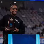 Nikki Smith stands with a trophy at the awards ceremony of the 2026 NCAA Gymnastics Championships