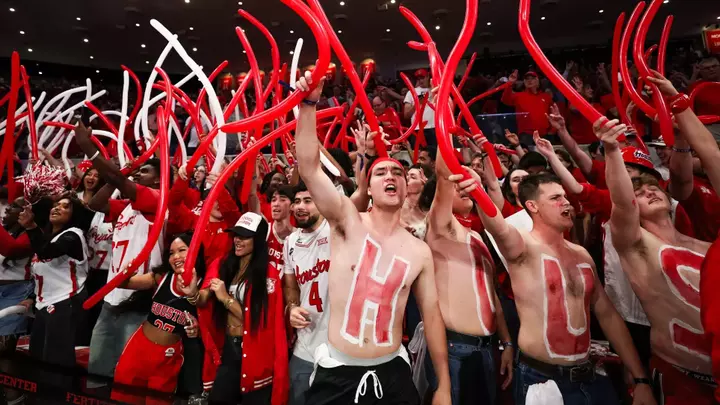 Students cheer with balloons during a game inside Fertitta Center