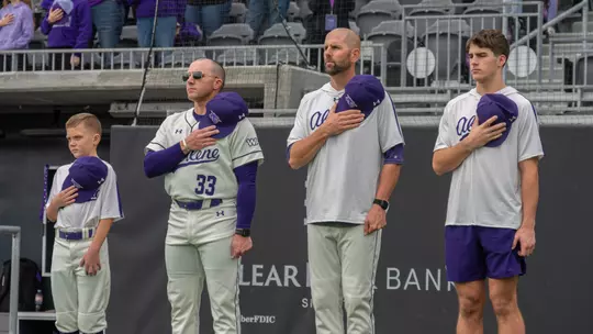 ACU baseball coaches Blaze Lambert and Rick McCarty stand for the national anthem before an opening series game vs. St. Thomas in Feb. 2026