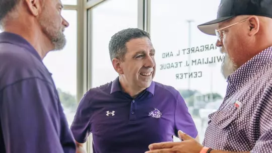 ACU vice president for athletics Zack Lassiter talks to two fans
