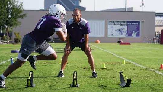 Trae Hill runs a drill with running backs coach Clark Harrell motivating on July 29, 2026