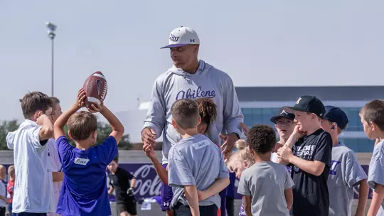 Joel Filani talks with campers at a youth football camp put on by ACU.