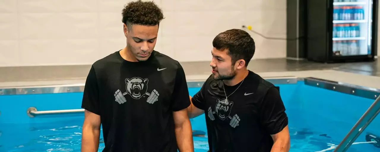 Michael Allen talks to football teammate before he baptizes him in the wave pool in the football facility