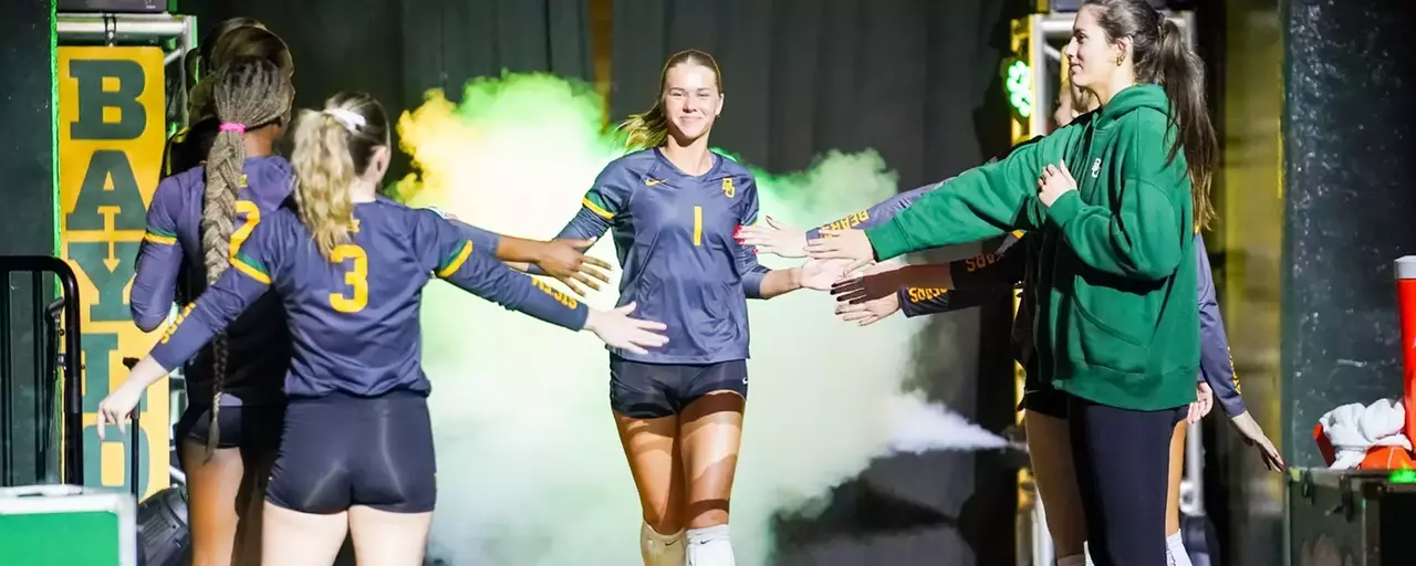 Harley Kreck runs out of the tunnel with players high fiving her before a home match