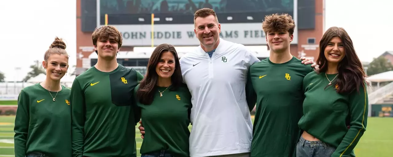 Football coach Joe Klanderman poses with 5 family members on the football field