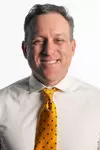 Joey Scrivano smiling in headshot in front of white backdrop