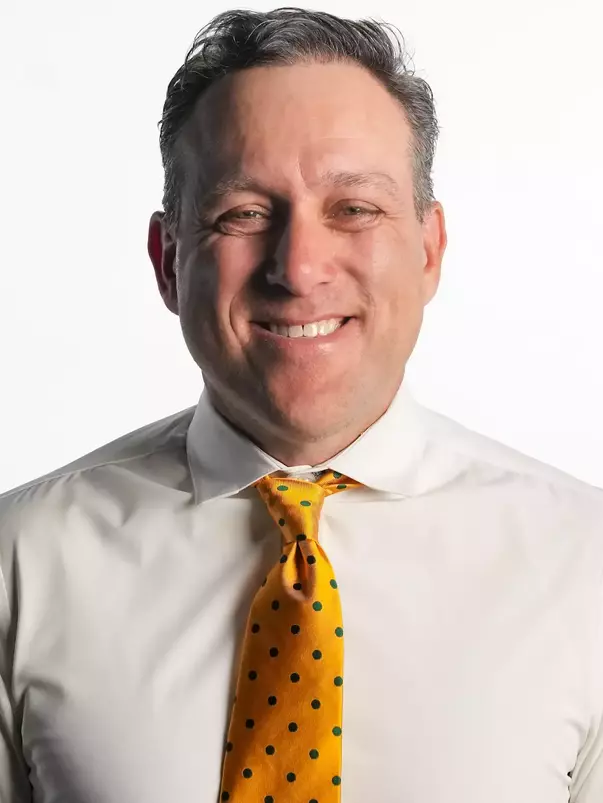 Joey Scrivano smiling in headshot in front of white backdrop