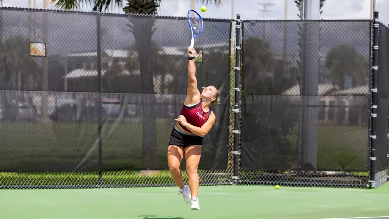 Marra Bruce reaching up to hit the tennis ball