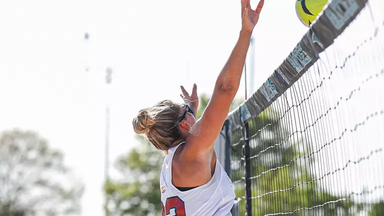 Beach Volleyball player jumps at the net to block