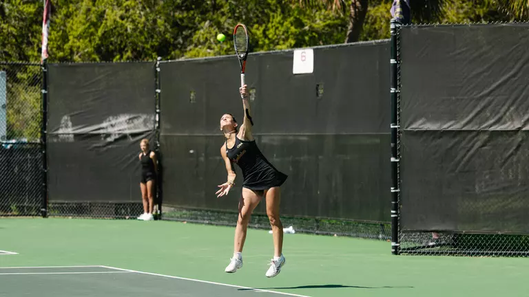 Jaiden McKee serves tennis ball