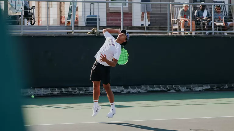 Eddie Vo serves tennis ball