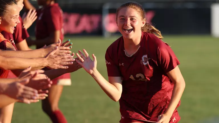 Emma Stankunas running through the starting lineup line and smiling