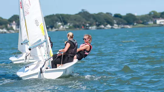 Women's sailing practicing on the water in their boat.