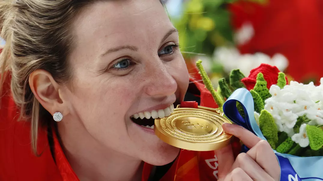 Laura Stacey '16 bites her gold medal at the 2022 Winter Olympics