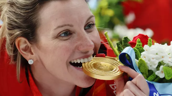 Laura Stacey '16 bites her gold medal at the 2022 Winter Olympics