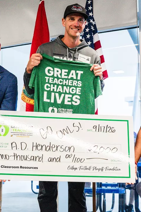 Vice President and Director of Athletics Josh McCowan and Hagerty Family Head Football Coach Zach Kittley presenting a check to A.D. Henderson University School