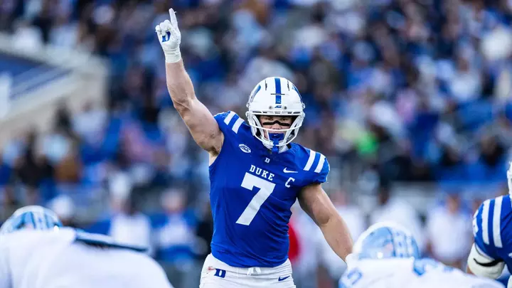Duke linebacker Nick Morris Jr., wearing a white helmet, blue jersey and white pants, holds a finger in the air and points to the sky against North Carolina on October 17, 2026.