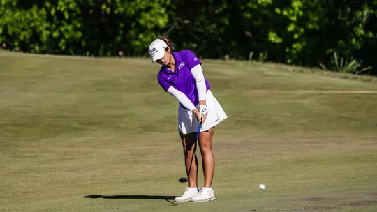 Kirstin Angosta chips off the fringe of the green wearing a purple shirt and white sleeves