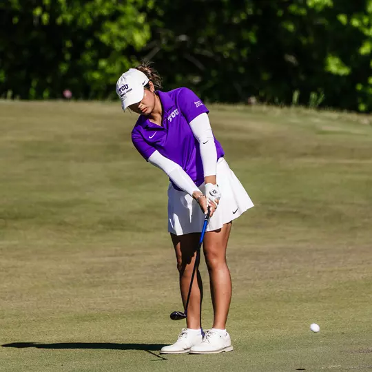 Kirstin Angosta chips off the fringe of the green wearing a purple shirt and white sleeves