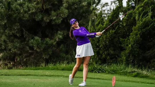 Gracie McGovern holds her follow through on a tee shot wearing a purple long-sleeve shirt