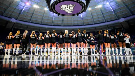 TCU Volleyball players stand on the baseline for the national anthem.