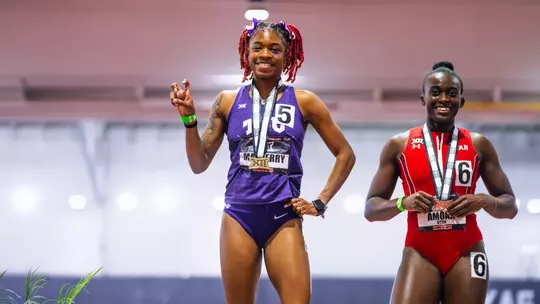 Indya Mayberry stands atop the podium with a gold medal after winning the 200m